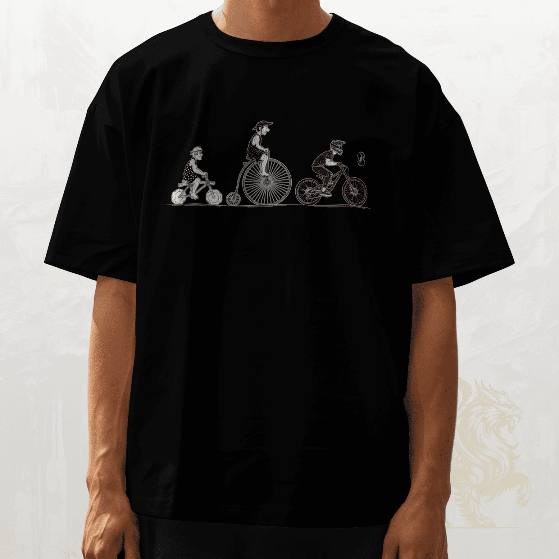 A person wearing a black short-sleeve T-shirt with a white line-art graphic across the chest showing three figures riding bicycles, photographed against a light neutral background.