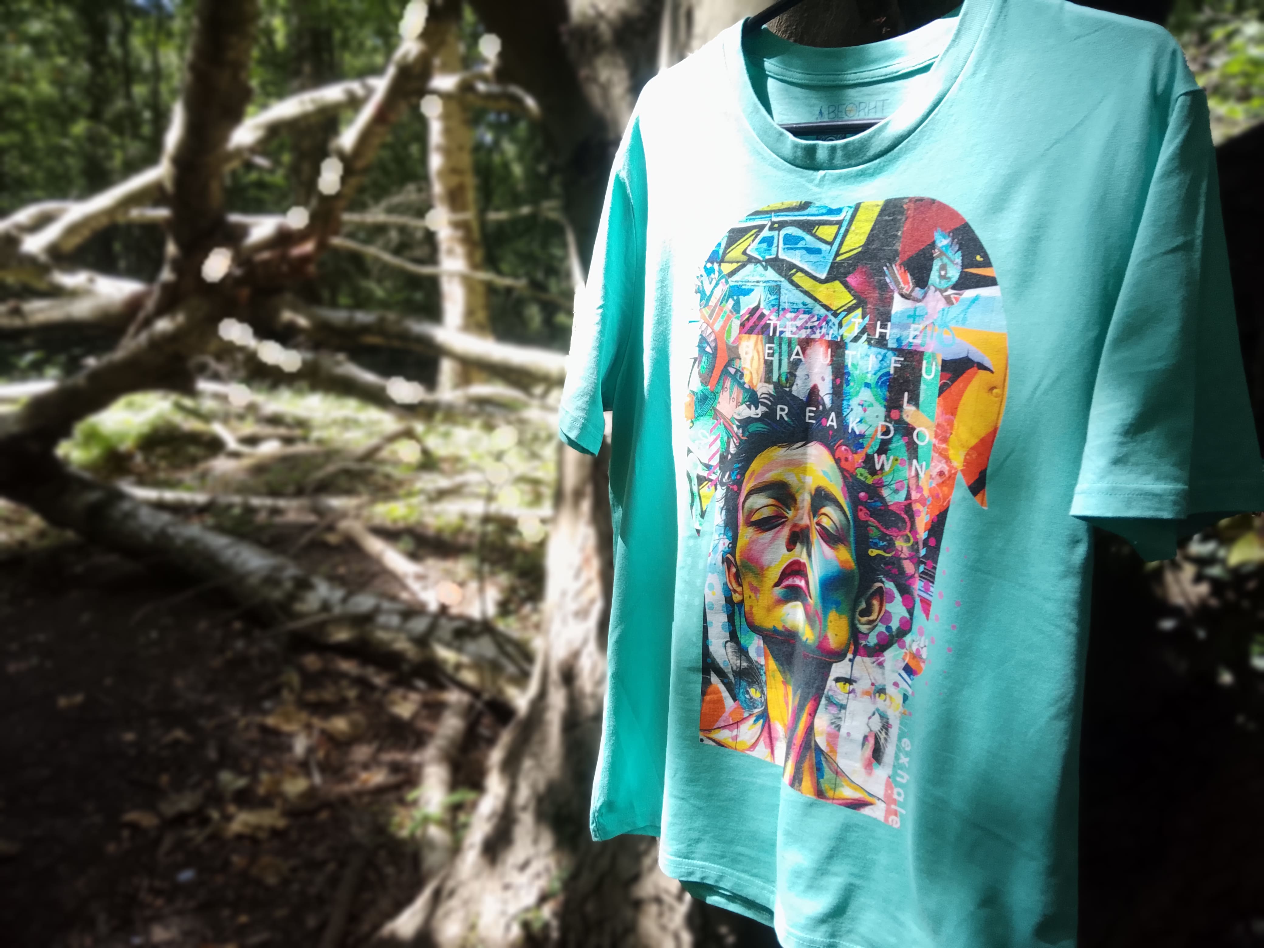 Turquoise t-shirt with a colorful graphic design in a forest setting