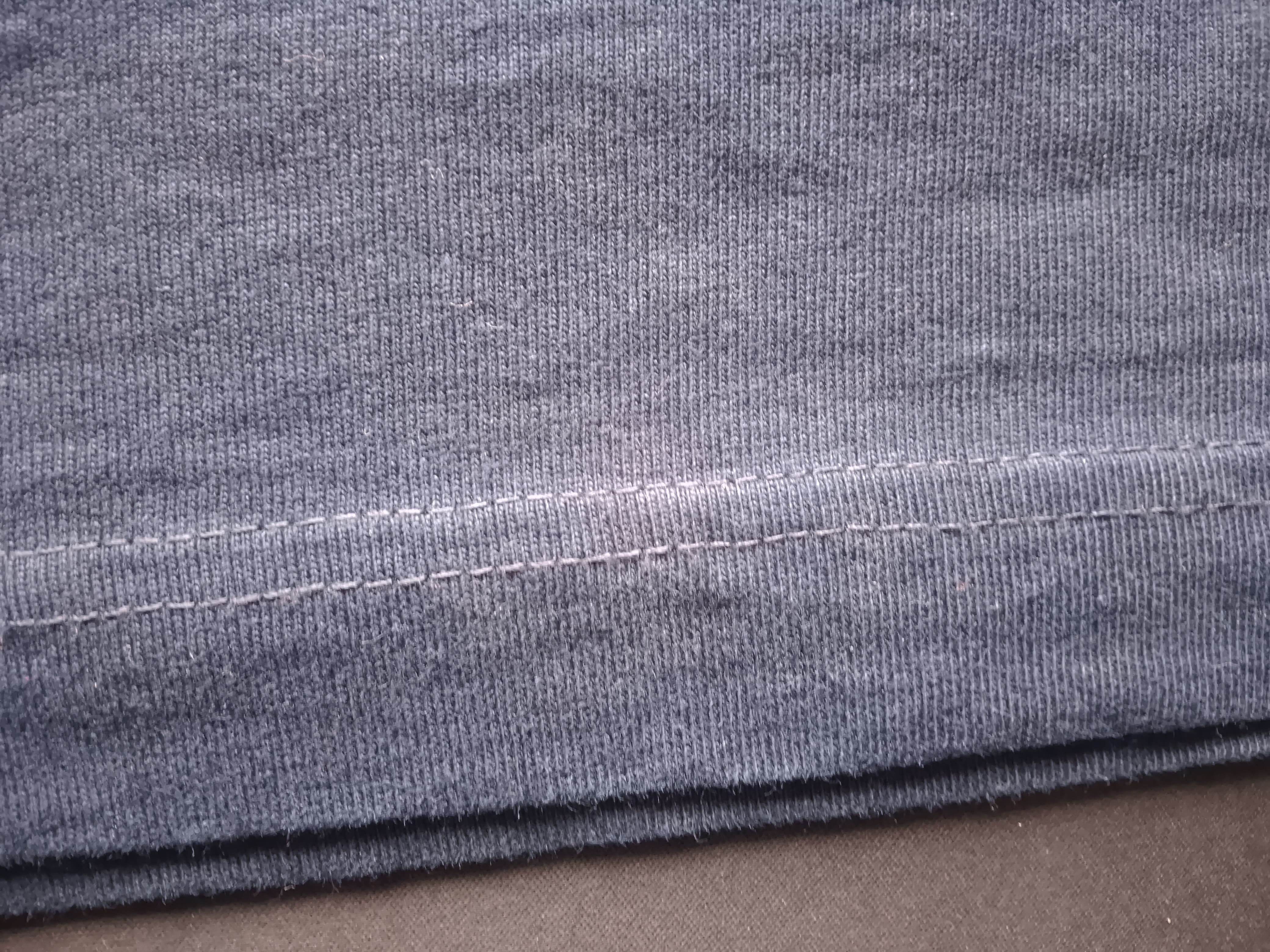 Close-up of gray fabric with a visible seam on a brown surface
