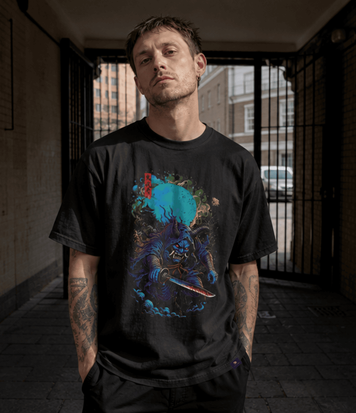 A man wearing a black graphic t-shirt with a detailed blue and red samurai warrior print, standing in a dark alleyway.