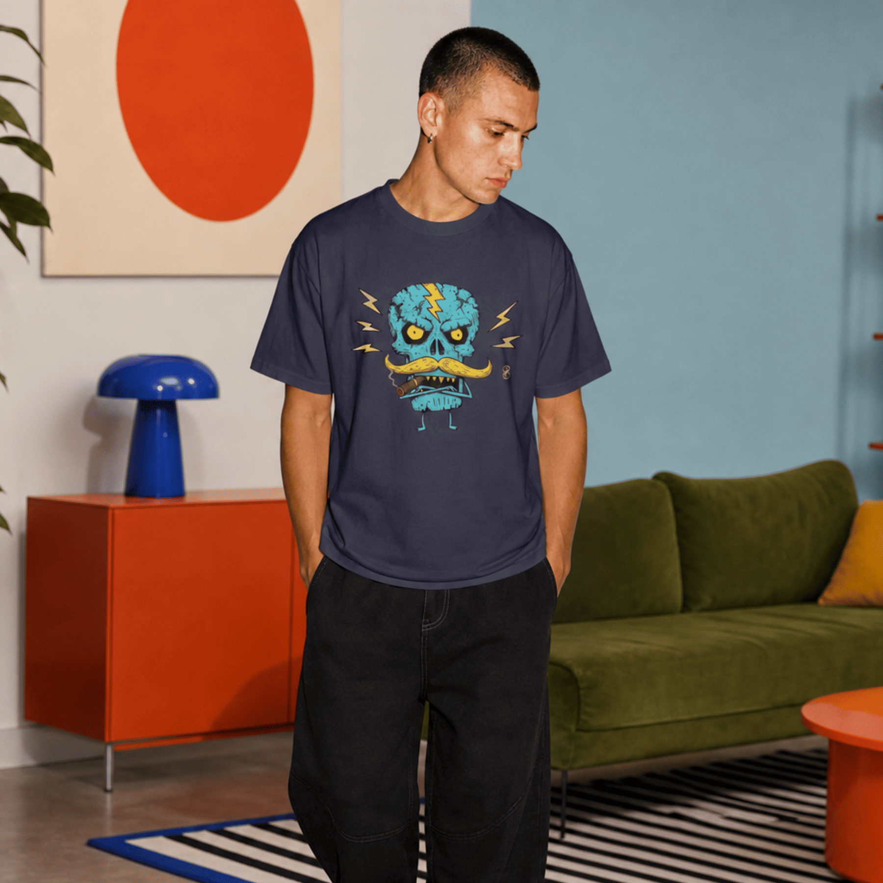 Man wearing a t-shirt with a blue graphic design in a modern living room.