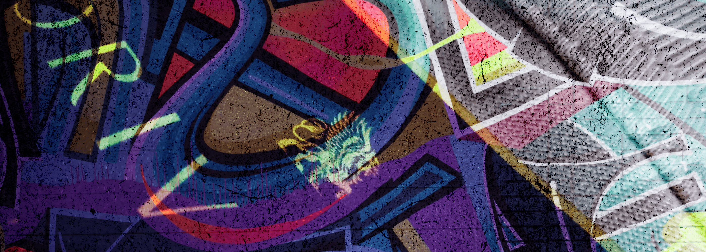 Close-up of colourful graffiti art with layered abstract lettering and geometric shapes in purple, blue, red, green, yellow, black, and grey.