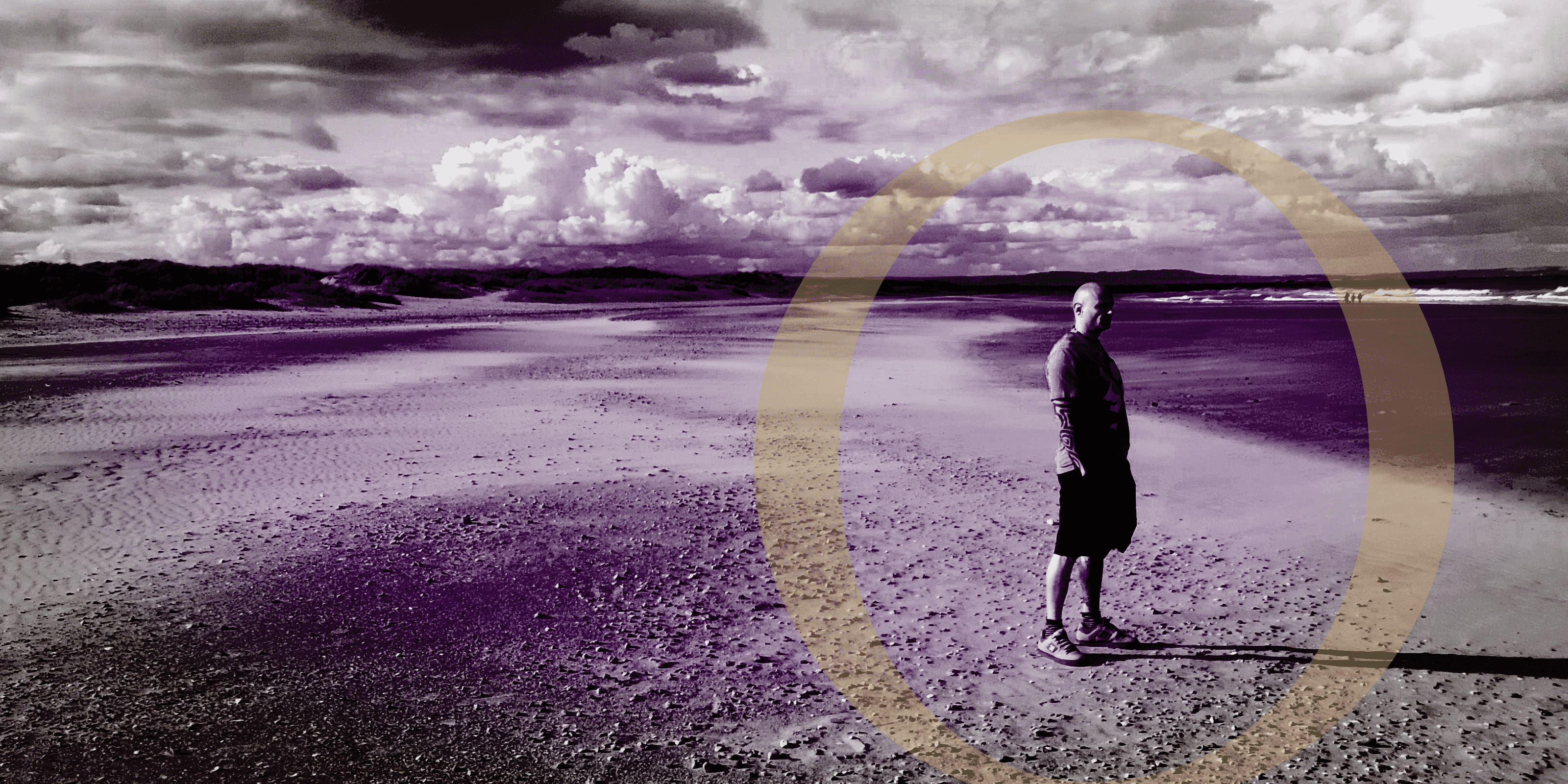 Person standing on a beach with a large circle overlay, black and white with purple tint