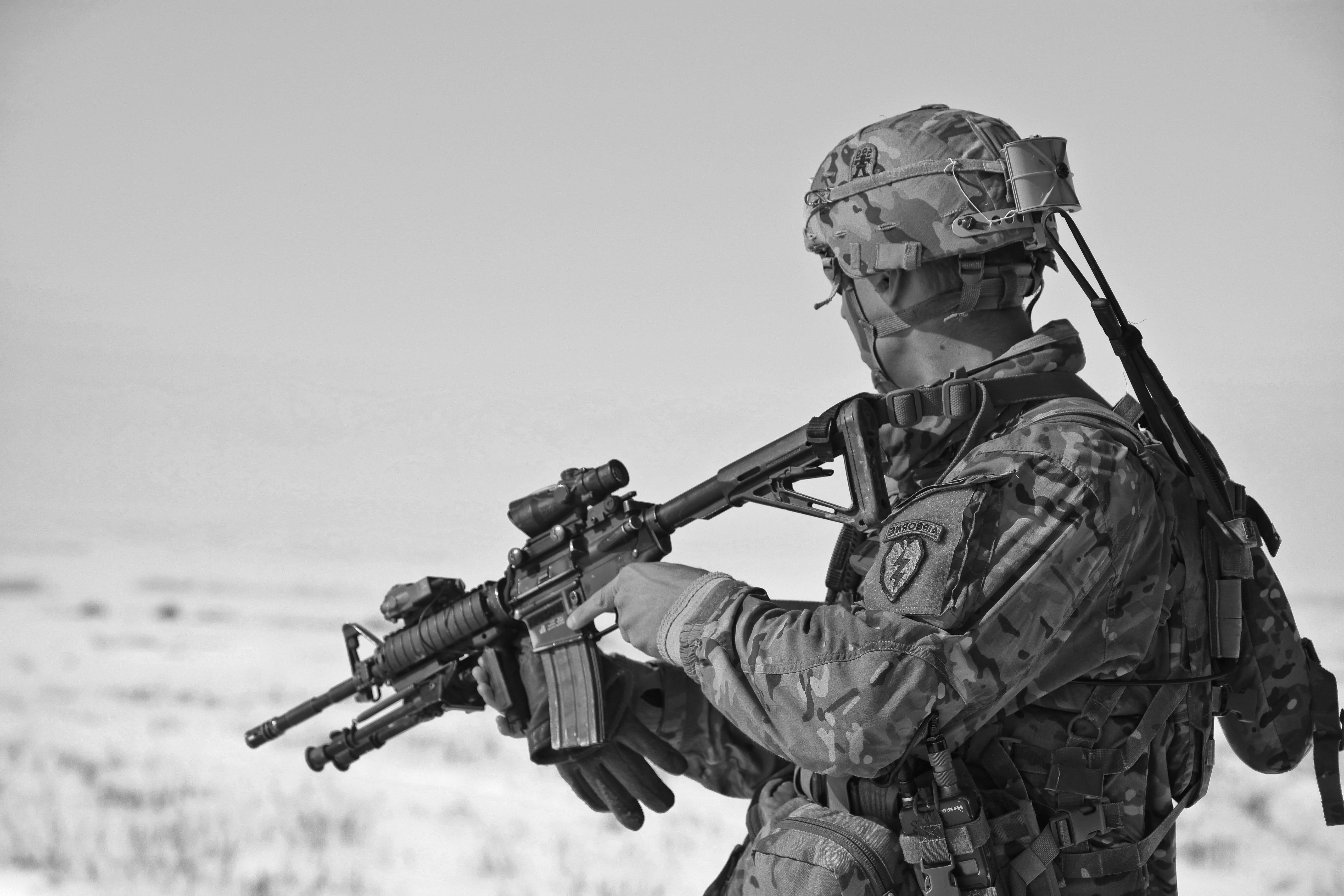 Soldier in camouflage gear holding a rifle with a snowy background
