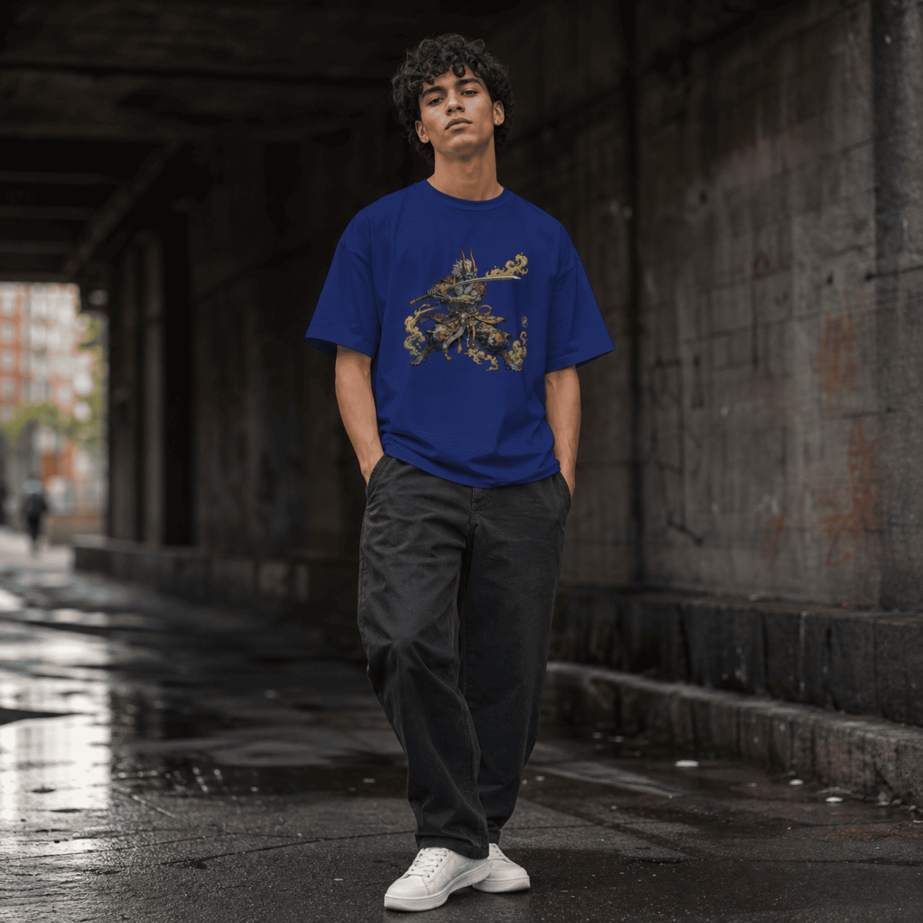 Person wearing a blue t-shirt with a Oni Warrior design, standing under an overpass.