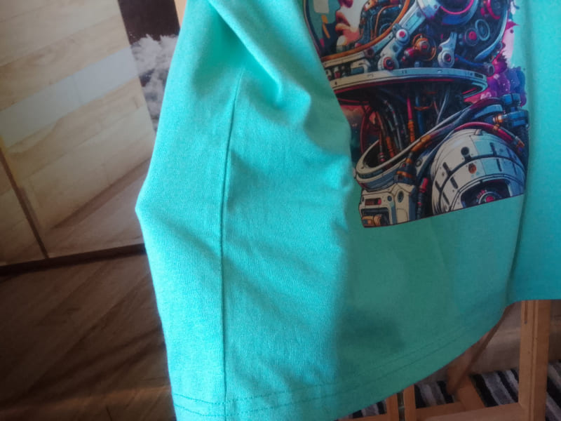 Turquoise shirt with a colorful graphic on a wooden surface