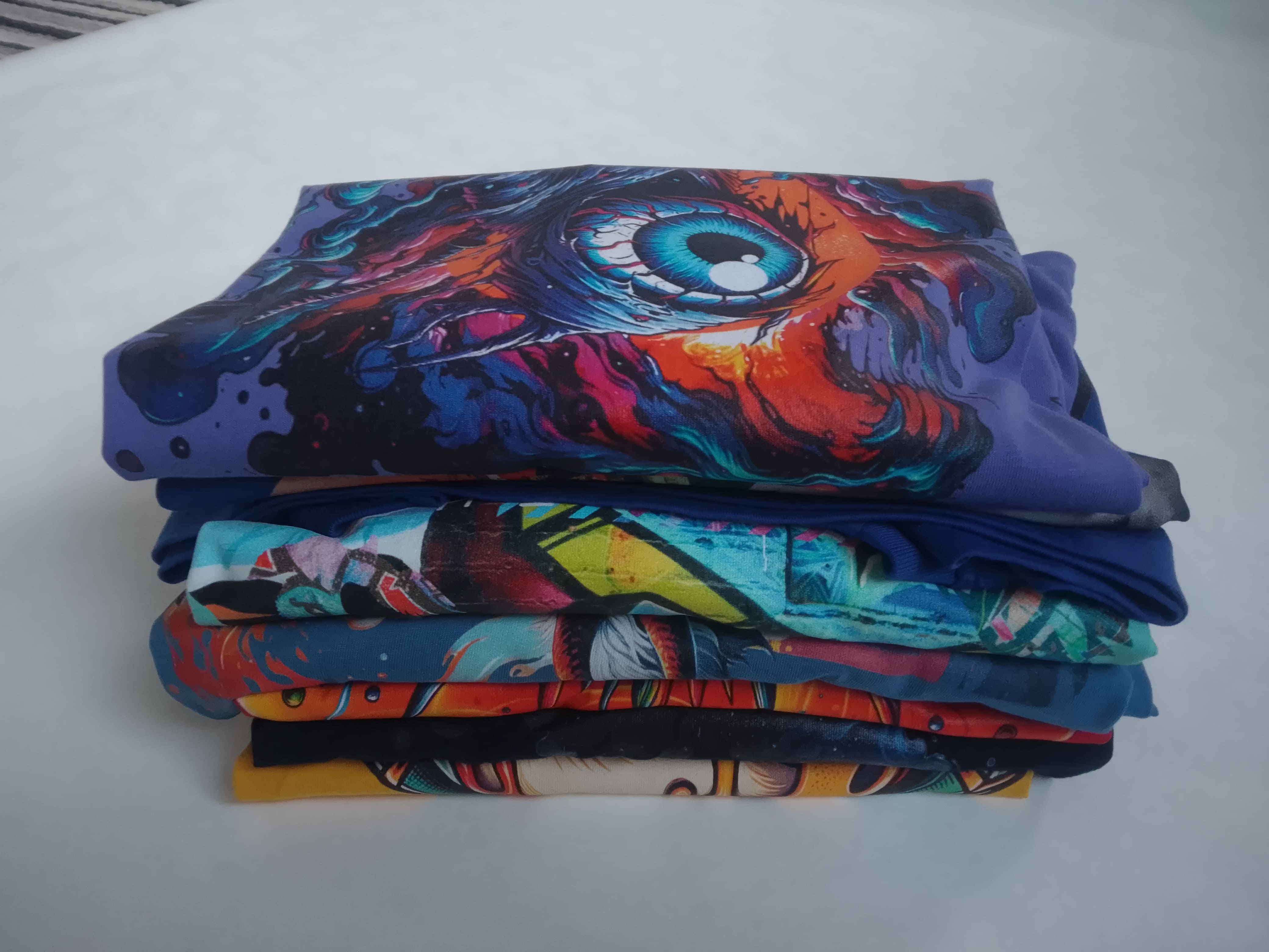 Stack of colourful fabric with abstract designs on a white surface