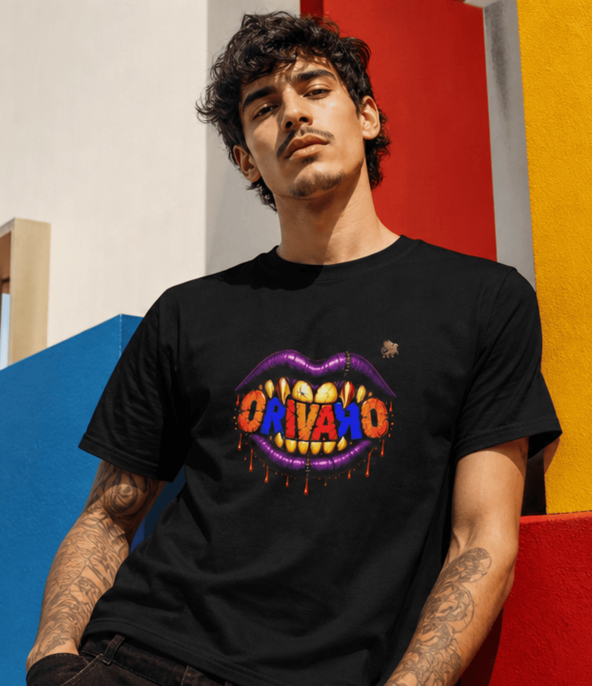 A man wearing a black t-shirt with a colourful graphic of dripping purple lips and the word 'ORIVARO' in orange, yellow, and red letters, posed against a vibrant geometric background of red, yellow, and blue blocks.