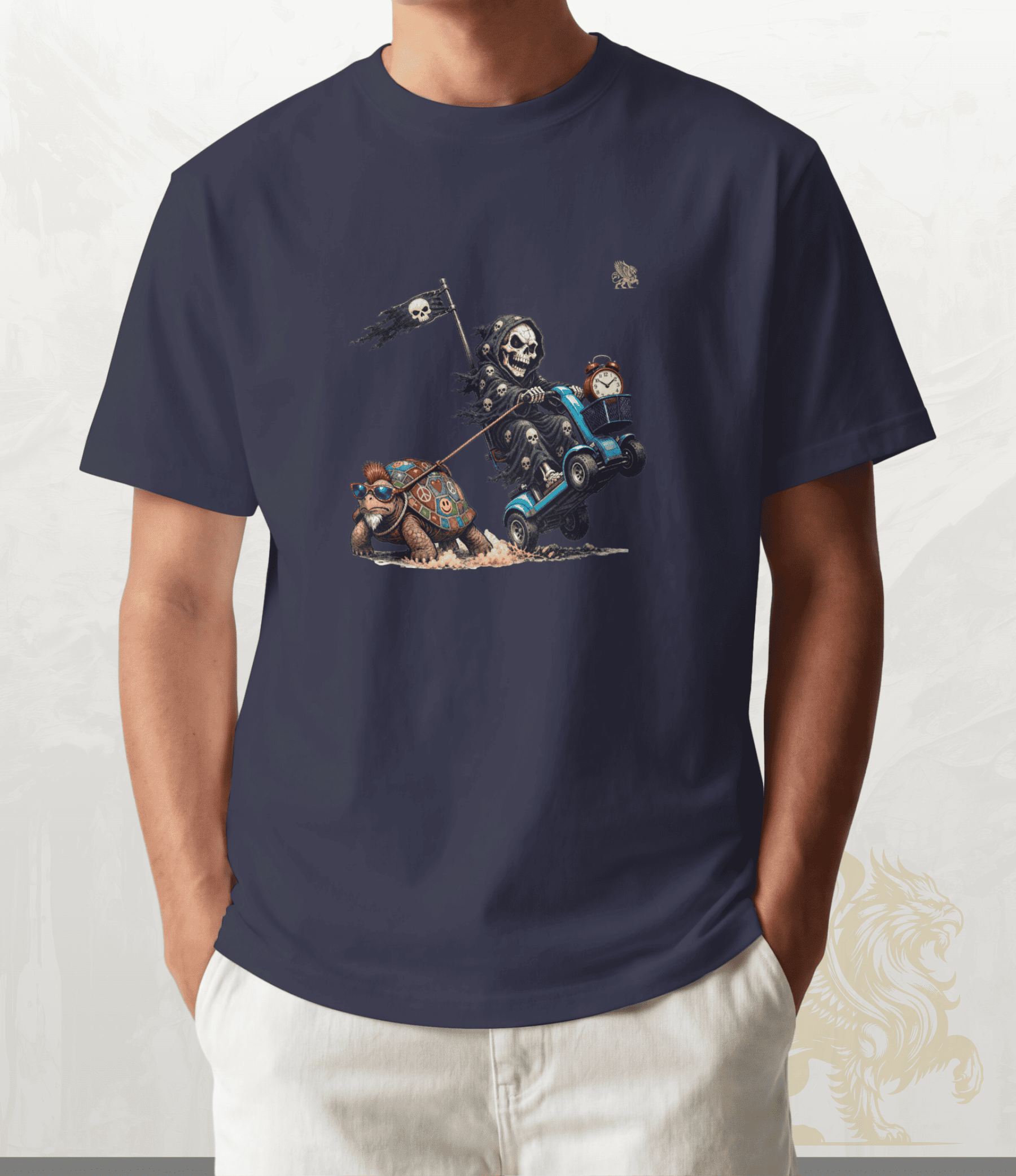 A man wearing a navy blue t-shirt with a graphic print of a skeleton knight on a blue cart pulling a decorative turtle, paired with off-white pants.