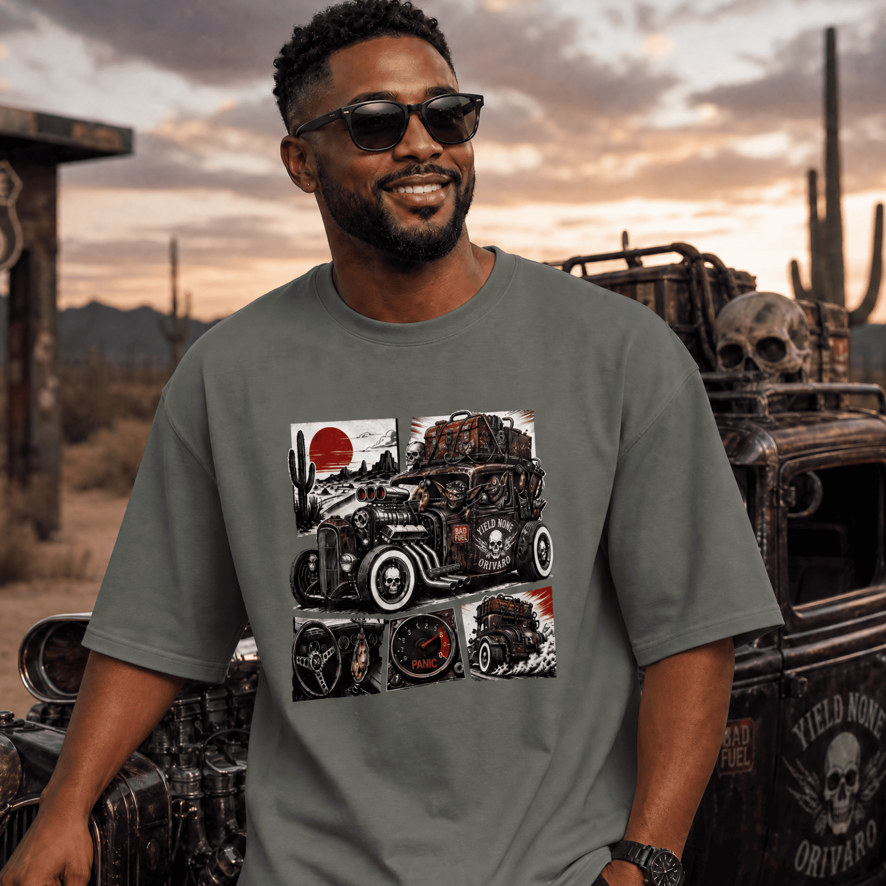 Man wearing a t-shirt with a graphic design of an old truck in a desert setting, standing in front of a vintage truck.