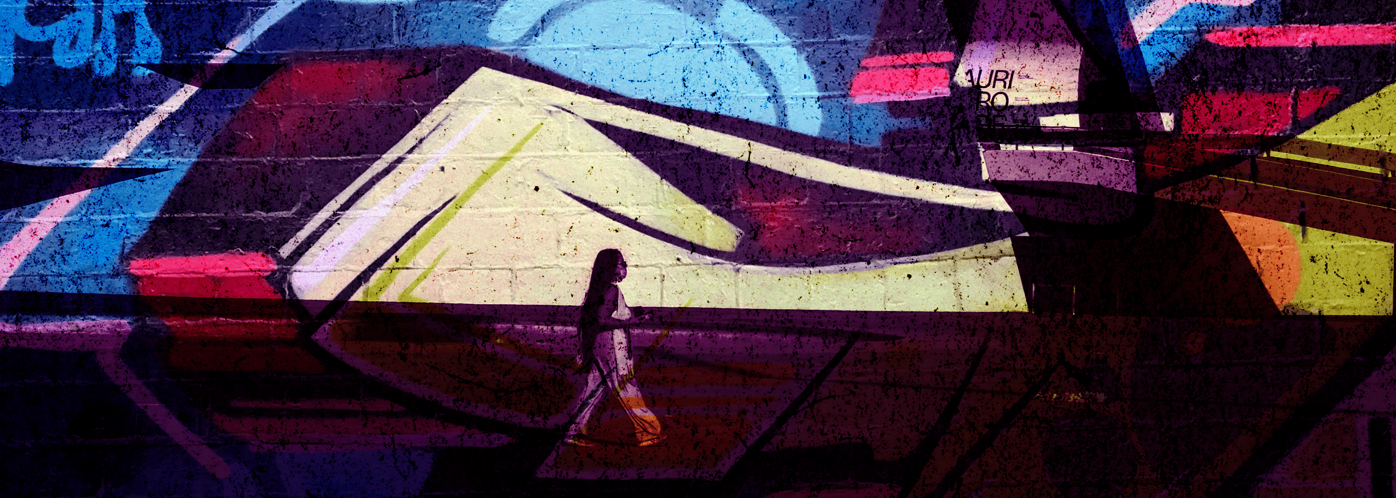 A colourful graffiti mural with a large geometric shape in pale yellow and red, overlaid with a dark silhouette of a person carrying a bag, set against a background of blue, purple, and red paint.
