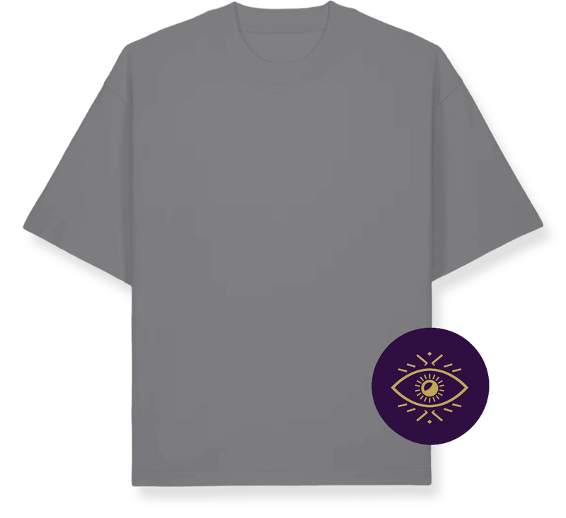 A flat-lay graphic of a grey short-sleeve t-shirt with a dark navy/black drop shadow, featuring a circular purple emblem with a gold eye design on the lower right side, set against a solid green background.