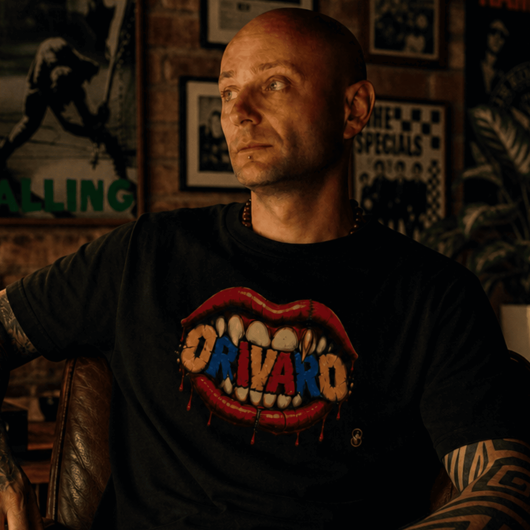 Man (aka. Founder of Orivaro) - wearing a black t-shirt with colourful graphic design in a dimly lit room.